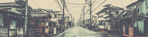 A quiet Japanese residential street with narrow sidewalks, small minimalist houses, clean lines, muted colors, overhead power lines, soft natural daylight, calm peaceful atmosphere