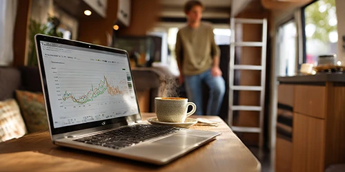 A calm interior scene inside a motorhome a table in the foreground with a laptop open showing simple stable charts and clean app interface no dramatic spikes a cup of coffee beside the laptop warm natural light minimal and organized workspace
